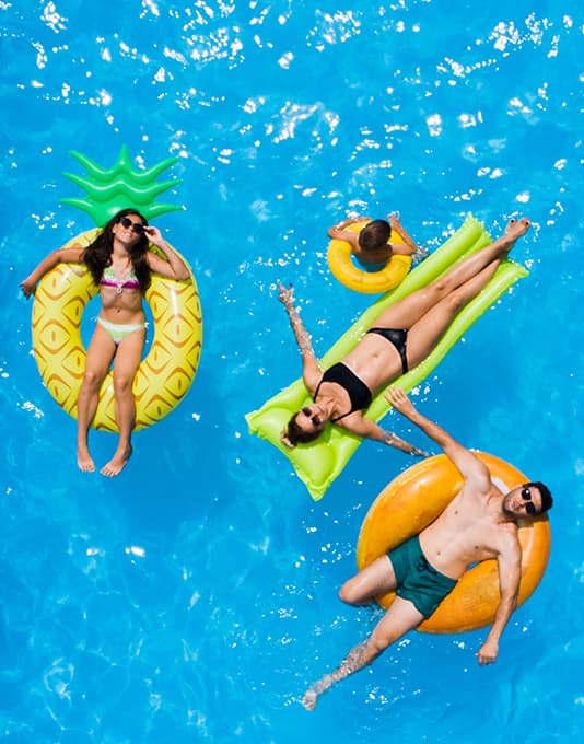 Family relaxing on floats in a backyard pool